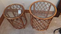 Front view of two cane tables side by side, showing glass tops and woven cane frames.