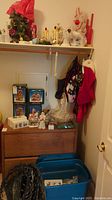 Photo of shelf with red Christmas stockings hanging, porcelain figurines on the dresser, Christmas lights, and candles on upper shelf.