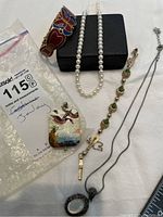 Lot overview showing all jewellery items including cloisonne bracelet and pendant, pearl necklace, gold bracelet, and silver pendant necklace