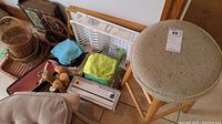 Photo showing round woven wicker seat stool, assorted baskets, trays, kitchen cloths, salt and pepper shakers, and dish racks.