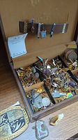 Wooden box interior holding multiple compartments filled with cufflinks, tie bars and pins