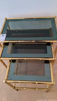 Top view of three brass framed nesting tables with black tinted glass tops stacked by size