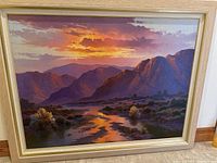 Full view of framed landscape painting showing desert valley, mountains, sky at sunset