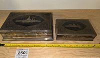 Both boxes side by side on wooden surface with measuring tape across front
