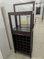 Full view of the espresso-colored bar cabinet showing the front with chrome wine glass rack, drawer, and bottle storage cubbies.