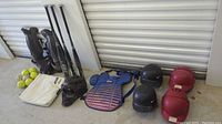 Photo showing multiple baseball equipment: batting helmets in black, red, blue; chest protector in blue; masks and knee protectors; home base pad; baseballs and bats.