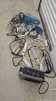 Collection of various cords, extension cords, and power strips on the floor