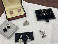 Photo of all six pairs of cuff links together, showing different designs and boxes