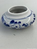 Side view of the mini ceramic container showing hand-painted blue floral motif on white glaze, with open mouth