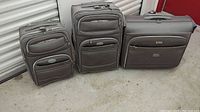 Photo of all three Delsey luggage pieces arranged side by side showing varying sizes and exterior pocket features.