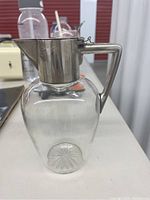 Full side view showing glass body with starburst pattern base and silver 800 mounted spout, handle and hinged lid.