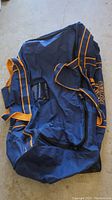 Full view of navy blue hockey bag with orange trim showing size and shape.