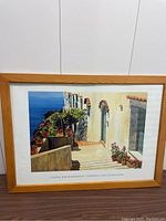 Frontal view of the framed artwork showing the Mediterranean scene with sea view in the background.