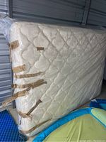 Side view of the queen mattress showing quilted white fabric cover and edges taped for reinforcement.