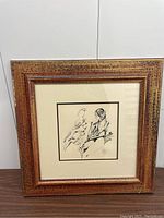 Framed black and white pen and ink drawing in wood frame displayed on table