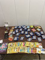 Wide view of multiple stacks and loose Pokémon cards including booster packs and loose cards spread on a table