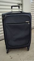 Front view of dark blue Samsonite luggage with zippered front pocket, retractable handle, and 360 spinner wheels.