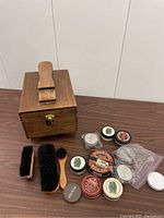 Wooden shoeshine box with shoe stand, multiple brushes and shoe polish tins
