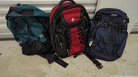 Three backpacks on floor showing colors, style and condition