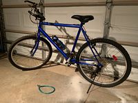 Side view of the full bicycle showing blue frame, black seat, handlebars, tires and water bottle.