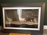 Front view of Dimplex electric fireplace showing full face glass panel with silver trim and dark gray frame.