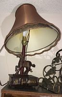 Full view of table lamp with brown fabric lampshade, wood horse figurine, and faux Odyssey book base.