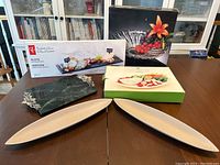 Photo showing slate serving board boxed, crystal bowl boxed and two bamboo trays on table