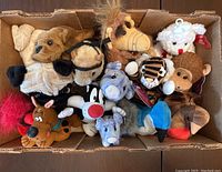 Top down view of various plush toys including ALF, dogs, tiger, monkeys, bears, with some tagged plush and a finger puppet.