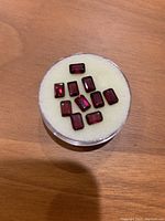 Ten red rectangular garnet stones displayed on a round foam pad.