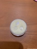 Three cabochon oval moonstone gems sitting on foam inside a clear round container.