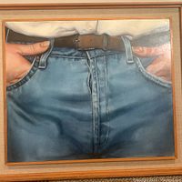 Full view of the framed painting showing the upper jeans and belt area with hands holding belt loops.