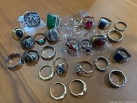 Overview of entire collection of 22 assorted rings on wood surface