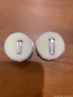 Two kunzite gemstones placed on white foam on a wooden surface, showing both stones side by side.