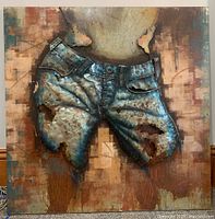 Front view of mixed media iron and hand painted 3D wall art showing burnt denim shorts with detailed rust and holes, mounted on abstract background.