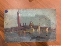 Small rectangular painting of Venice with gondolas and waterfront buildings under cloudy sky in muted colors on wood panel.
