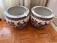Pair of round white ceramic planters with painted peacocks and flowers, decorative rim pattern