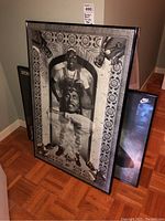 Black and white basketball print in black frame leaning against wall with two additional basketball prints partially visible