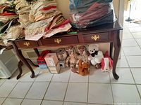 Front view showing wood console table with three drawers, brass handles, and items on and below the table (not included).