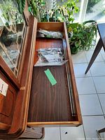 Long open wooden drawer with flatware pieces inside two plastic bags.