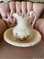 Pitcher and basin set placed on a pink couch showing the entire set.