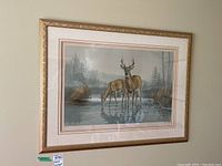 Full view of framed print showing the deer and natural setting, with the frame featuring gold decorative edging.