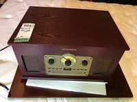 Front and top view of the Sylvania Nostalgia 5-in-1 turntable radio showing wood grain finish and general condition.