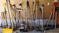 Wide shot of entire lot showing multiple shovels, rakes, pitchfork, sledgehammer, and other yard tools