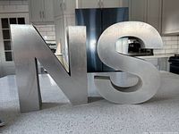 Silver heavy metal letters 'N' and 'S' on a kitchen counter