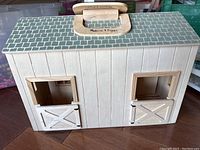Closed Melissa & Doug wooden barn with roof handle and two stable doors.