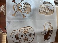 Close-up image of paintable cling transfers with skull and sugar skull designs on transparent sheets