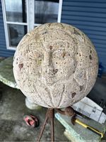 Close-up front view of one agate sun sphere showing facial carving details