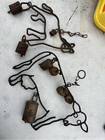 Metal animal-shaped wind chimes with multiple rusty bells on a white surface