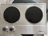 Top view of stainless steel hot plate with two burners and two control knobs.