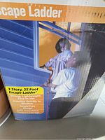Box showing packaging of the emergency escape ladder with a man holding a child on the window demonstrating usage. Ladder is 3 stories, 25 feet long, lightweight, tangle-free design.